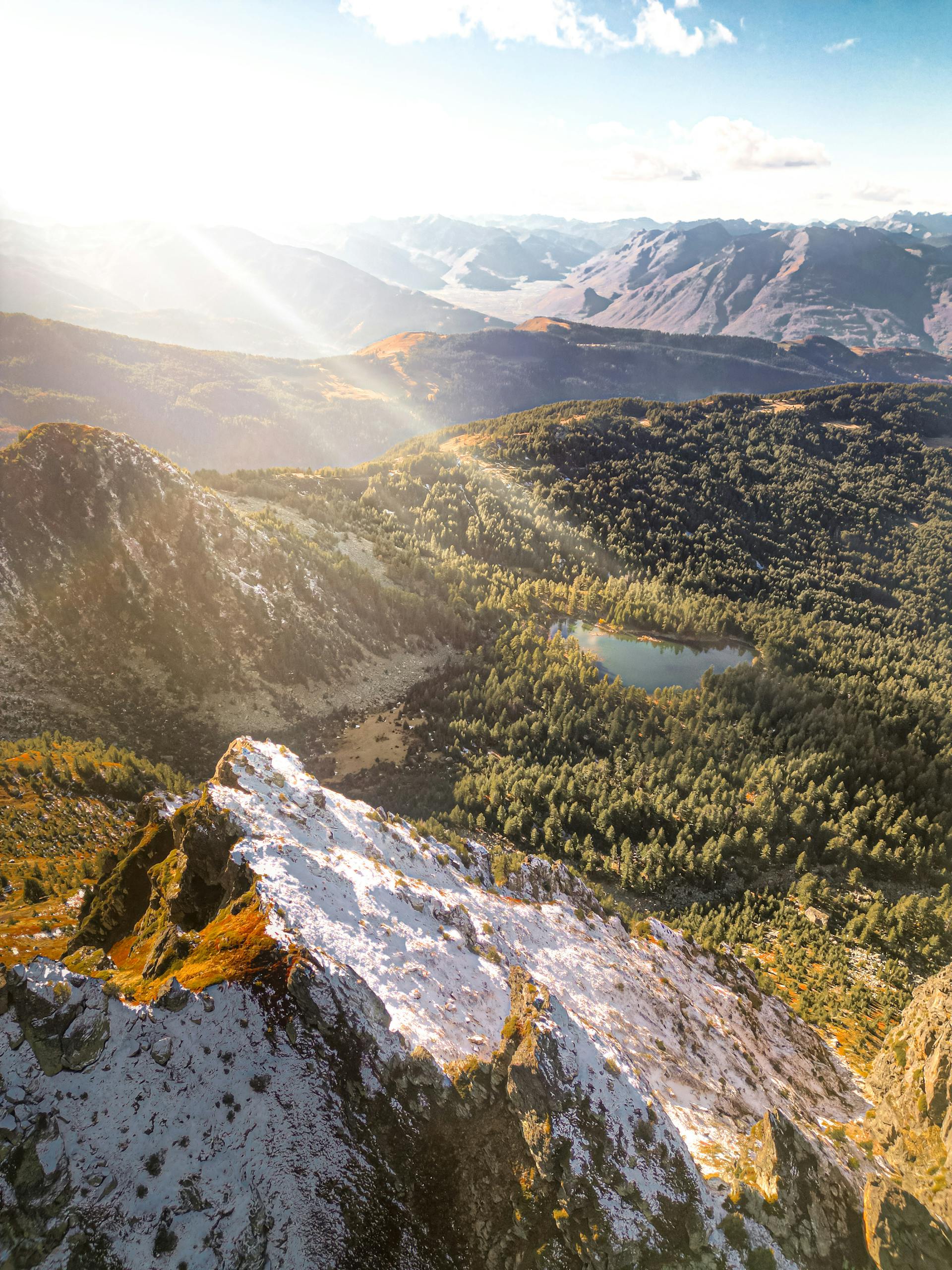 A breathtaking aerial view of a forested mountain landscape with a serene lake.