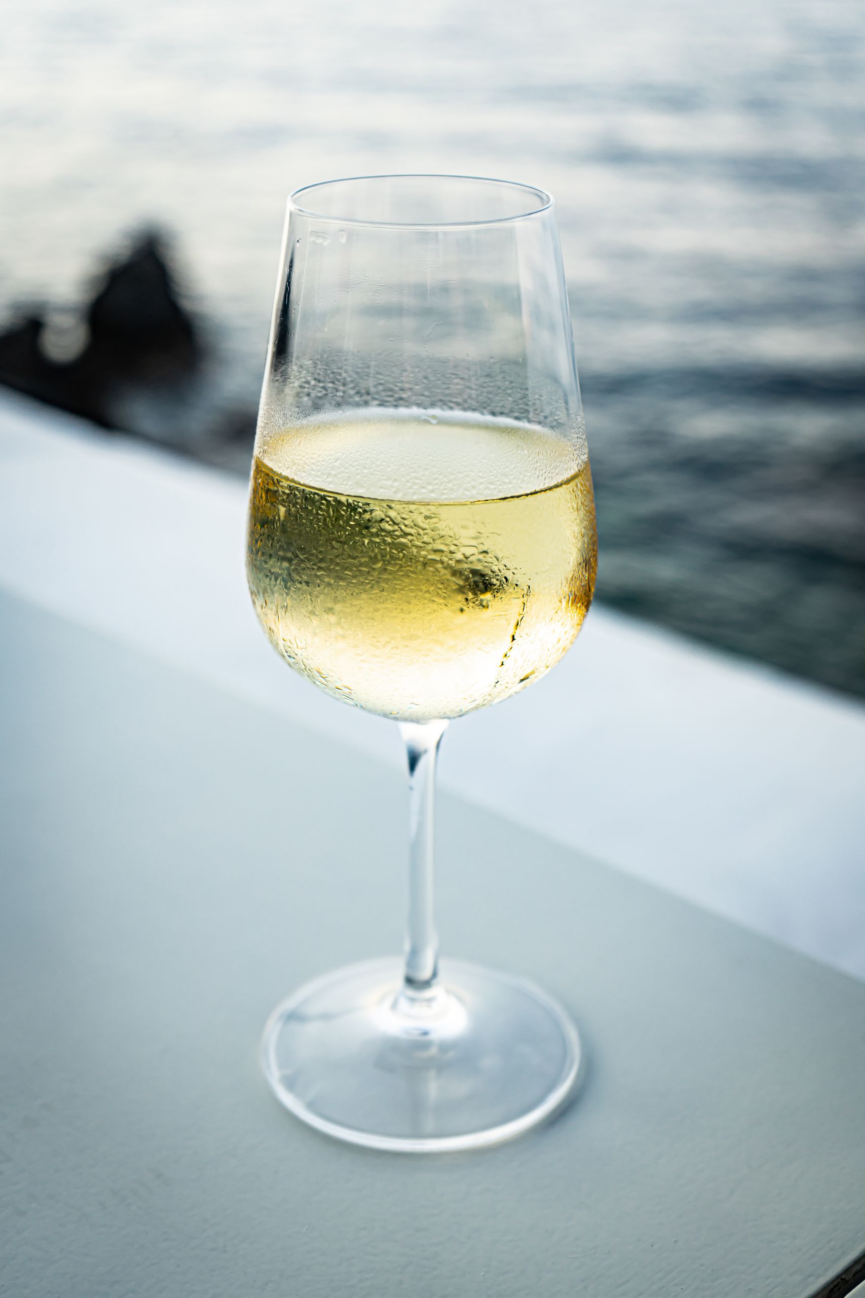 Refreshing glass of white wine by the sea, perfect for relaxing moments.